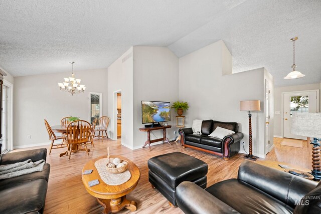 living room featuring a textured ceiling, a chandelier, baseboards, vaulted ceiling, and wood finished floors