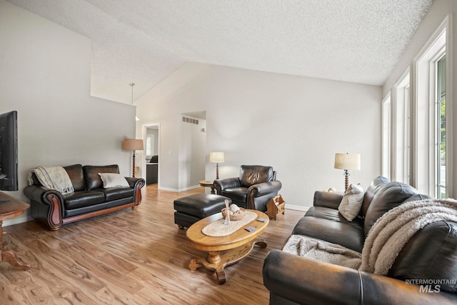living room featuring baseboards, wood finished floors, a textured ceiling, and vaulted ceiling