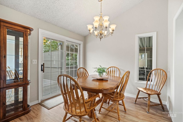 dining space featuring a chandelier, light wood-type flooring, a textured ceiling, and baseboards