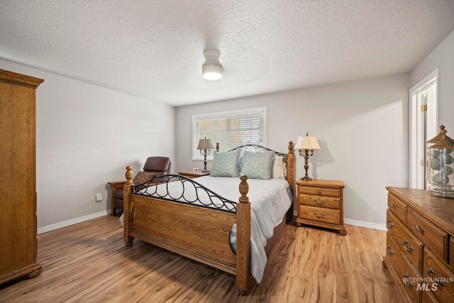 bedroom with light hardwood / wood-style floors and a textured ceiling