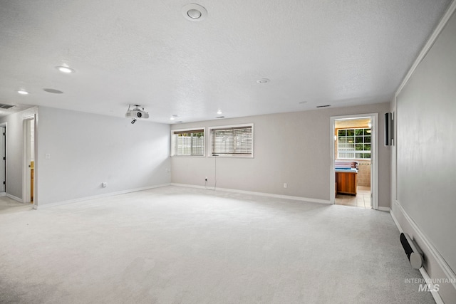 unfurnished room featuring a textured ceiling, visible vents, baseboards, recessed lighting, and light carpet