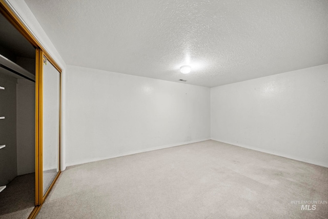 interior space with a textured ceiling, a closet, and light colored carpet