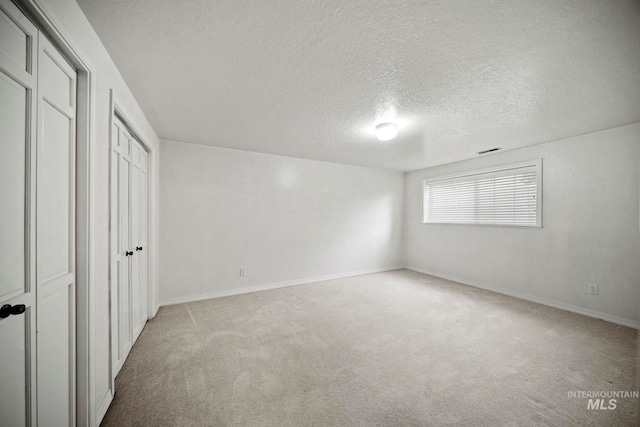 unfurnished bedroom featuring light carpet and a textured ceiling