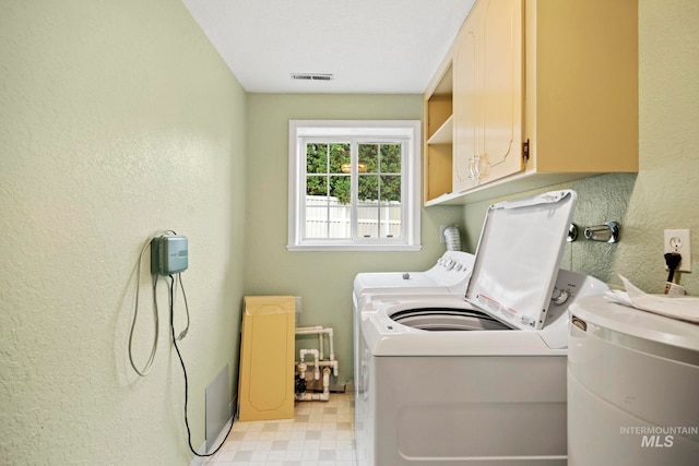 laundry room with cabinet space, washing machine and clothes dryer, visible vents, a textured wall, and light floors