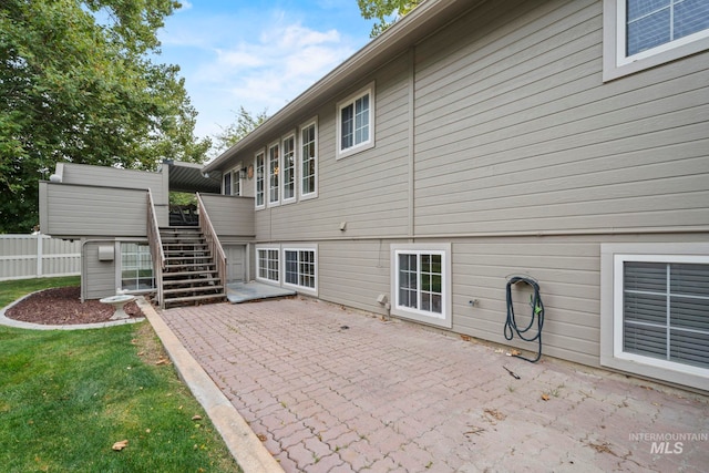 back of house featuring fence, stairway, a patio area, and a yard