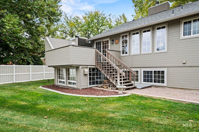 back of property with a lawn, stairs, a chimney, and fence
