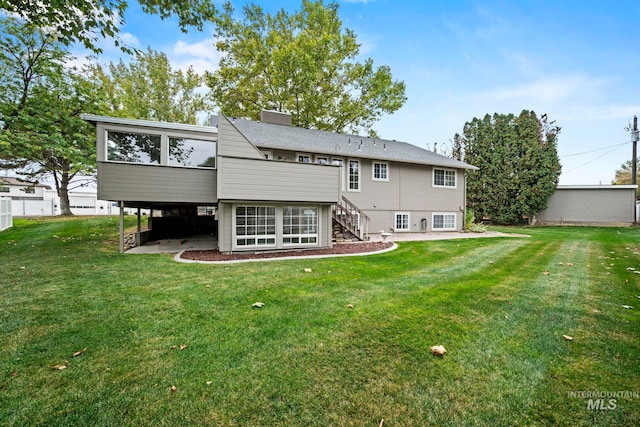 back of property with a chimney, a yard, stairs, and a sunroom