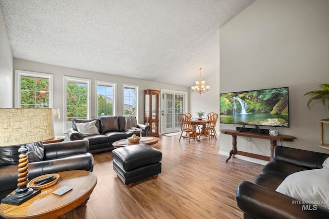 living room with hardwood / wood-style flooring, a textured ceiling, lofted ceiling, and a chandelier