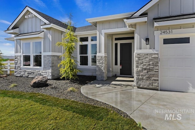 doorway to property featuring a garage, board and batten siding, driveway, and stone siding