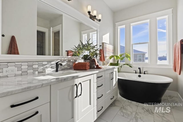 bathroom with a sink, double vanity, marble finish floor, backsplash, and a soaking tub