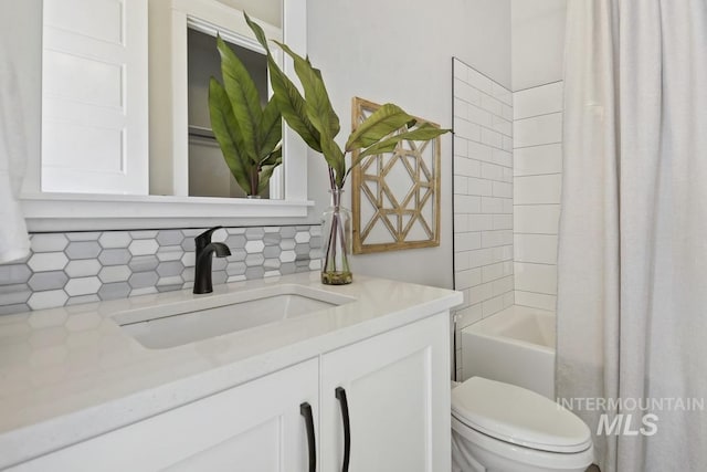 bathroom with vanity, shower / bath combo, toilet, and tasteful backsplash