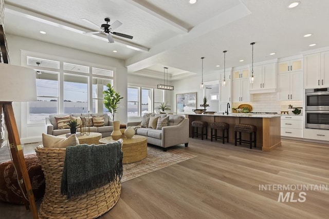 living area featuring light wood-style floors, ceiling fan, and recessed lighting