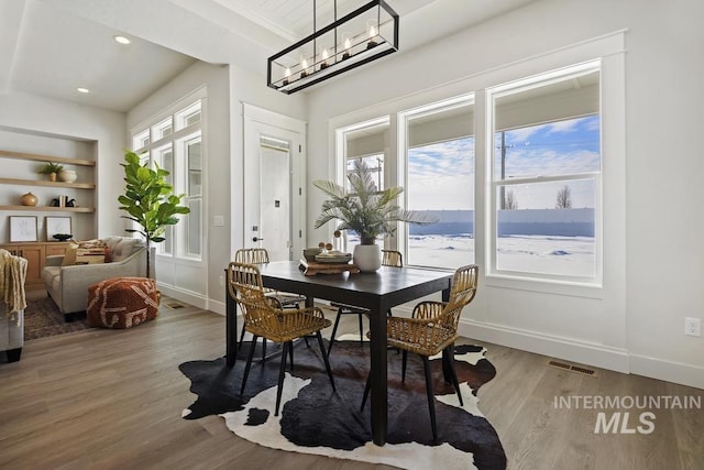 dining area featuring built in features, baseboards, wood finished floors, and visible vents