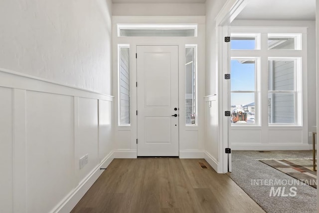 entryway featuring a wainscoted wall, visible vents, wood finished floors, and a decorative wall