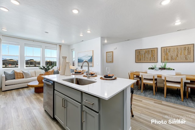 kitchen with an island with sink, sink, gray cabinetry, and light hardwood / wood-style floors