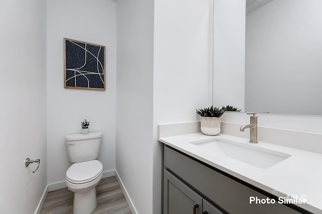 bathroom with hardwood / wood-style flooring, vanity, and toilet