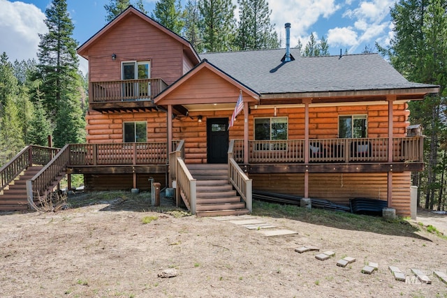view of front facade featuring stairway, a shingled roof, log exterior, and covered porch