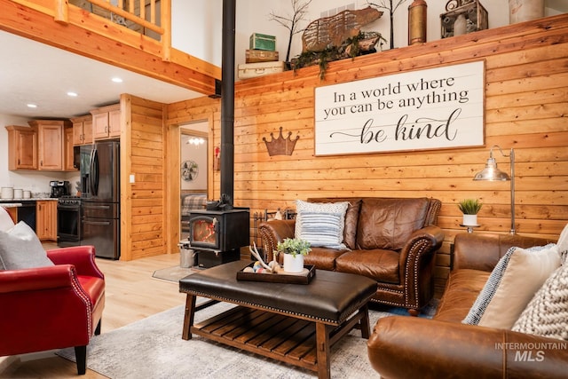 living area with a wood stove, recessed lighting, light wood-style flooring, and wooden walls