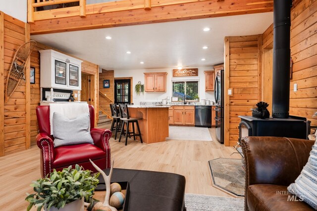 living area featuring a wood stove, light wood-type flooring, recessed lighting, and wood walls