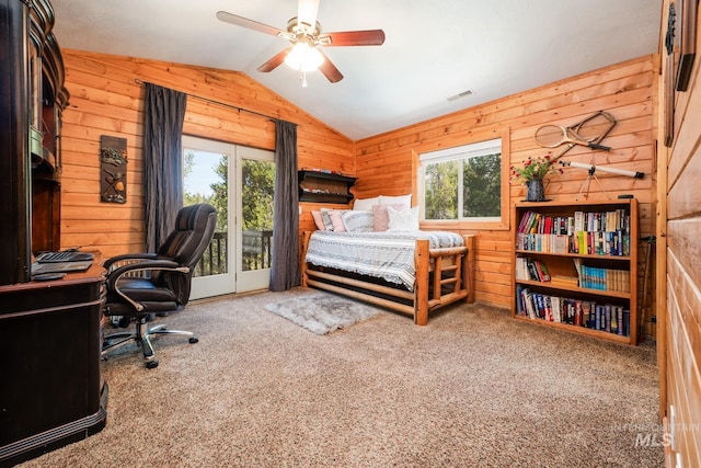 carpeted bedroom featuring wood walls, vaulted ceiling, access to exterior, an office area, and a ceiling fan