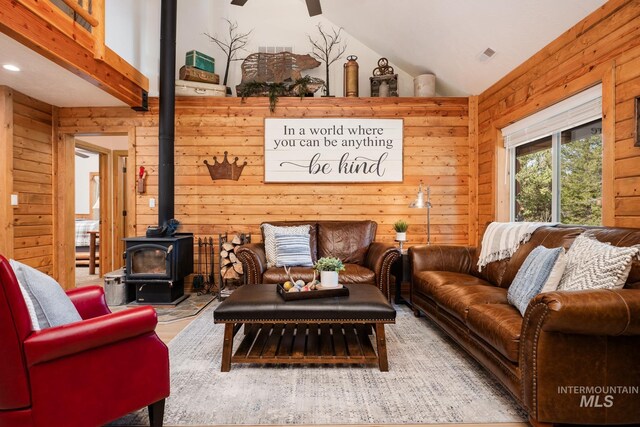 living room featuring wooden walls, vaulted ceiling, a wood stove, recessed lighting, and ceiling fan