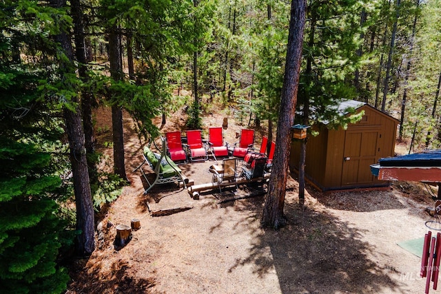 view of yard with a storage shed, an outbuilding, and a forest view