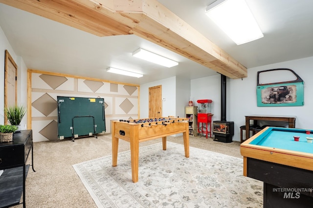 recreation room with a wood stove and carpet flooring
