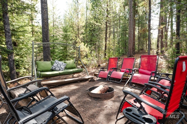 view of patio with an outdoor fire pit and a wooded view