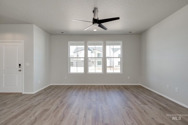 empty room featuring baseboards, ceiling fan, a textured ceiling, and wood finished floors