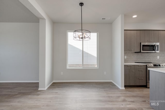 kitchen with stainless steel appliances, visible vents, decorative backsplash, light countertops, and a notable chandelier