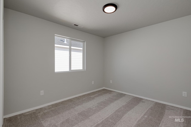 empty room with carpet, visible vents, and baseboards