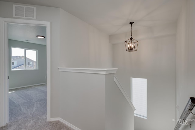 interior space with carpet flooring, an upstairs landing, visible vents, baseboards, and a chandelier