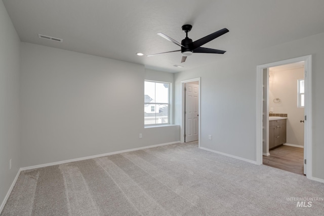 unfurnished bedroom featuring baseboards, multiple windows, light carpet, and visible vents