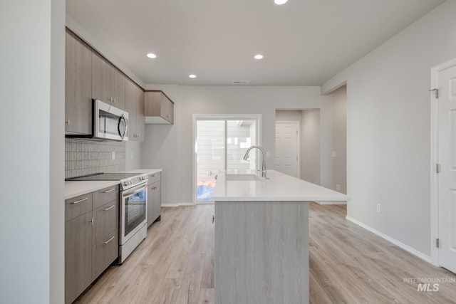 kitchen featuring light wood finished floors, light countertops, appliances with stainless steel finishes, and a sink