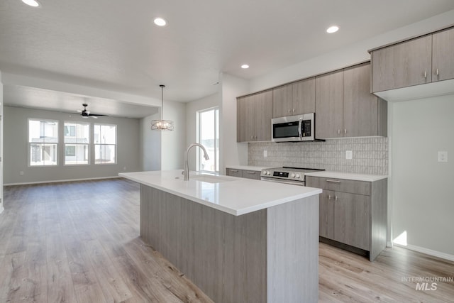 kitchen featuring a sink, appliances with stainless steel finishes, backsplash, modern cabinets, and light wood-style floors