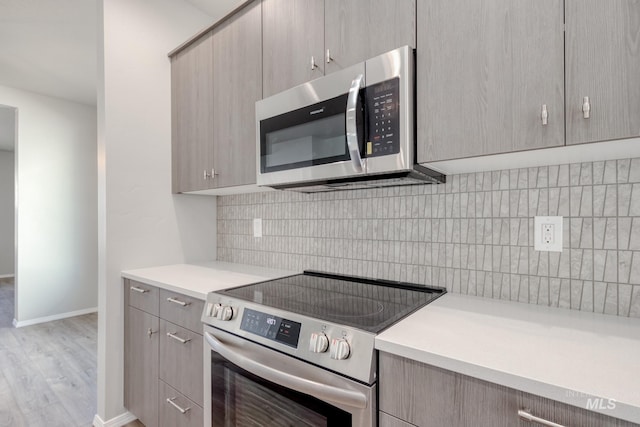 kitchen with stainless steel appliances, light countertops, light wood-type flooring, and gray cabinets