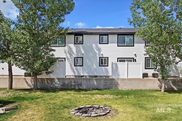 rear view of house featuring a fire pit and a lawn