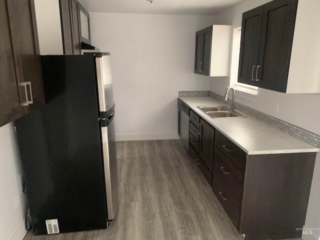 kitchen featuring dark brown cabinets, light hardwood / wood-style floors, stainless steel refrigerator, and sink