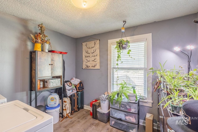 laundry area featuring washer / clothes dryer, a textured ceiling, wood finished floors, baseboards, and laundry area