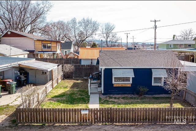 view of front facade with a fenced front yard, a shingled roof, and a front yard