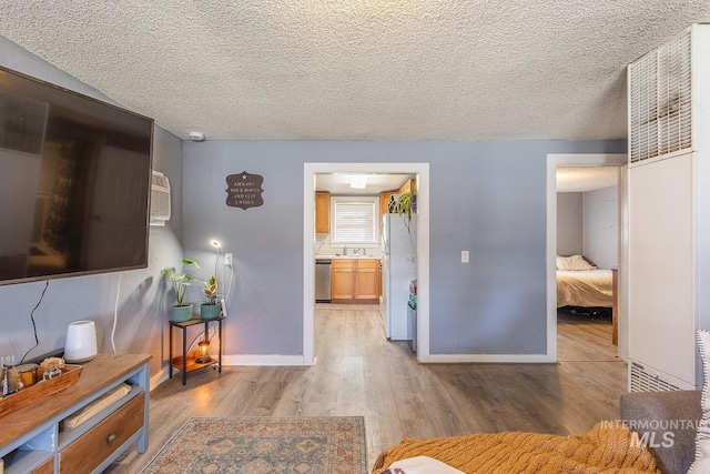 living area with light wood-style floors, baseboards, and a textured ceiling