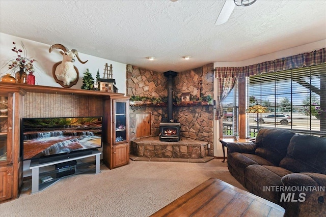 living room with carpet floors, a wood stove, and a textured ceiling