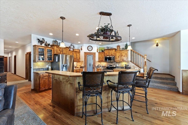 kitchen featuring a spacious island, appliances with stainless steel finishes, a kitchen bar, and decorative light fixtures