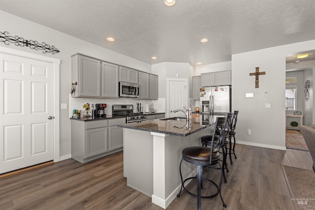 1417 Scranton Ave, Caldwell, ID 83605 - kitchen featuring appliances with stainless steel finishes, gray cabinetry, a sink, a breakfast bar, and dark wood-style floors