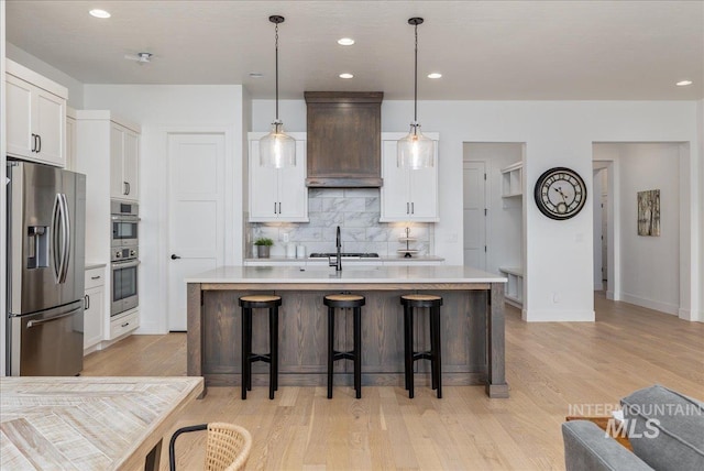 4923 W Canaston St, Meridian, ID 83646 - kitchen with appliances with stainless steel finishes, decorative backsplash, custom exhaust hood, light countertops, and light wood-style floors