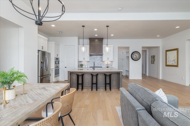 4923 W Canaston St, Meridian, ID 83646 - kitchen with appliances with stainless steel finishes, custom exhaust hood, backsplash, light countertops, and white cabinetry