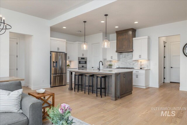4923 W Canaston St, Meridian, ID 83646 - kitchen featuring stainless steel appliances, a kitchen breakfast bar, light countertops, light wood-style floors, and backsplash