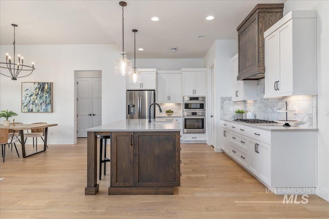 4923 W Canaston St, Meridian, ID 83646 - kitchen with appliances with stainless steel finishes, a sink, backsplash, light wood-style floors, and a chandelier