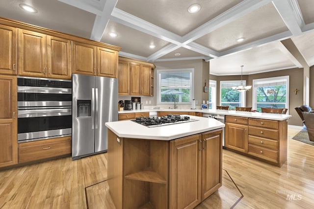 kitchen featuring brown cabinetry, a peninsula, light wood-type flooring, coffered ceiling, and stainless steel appliances