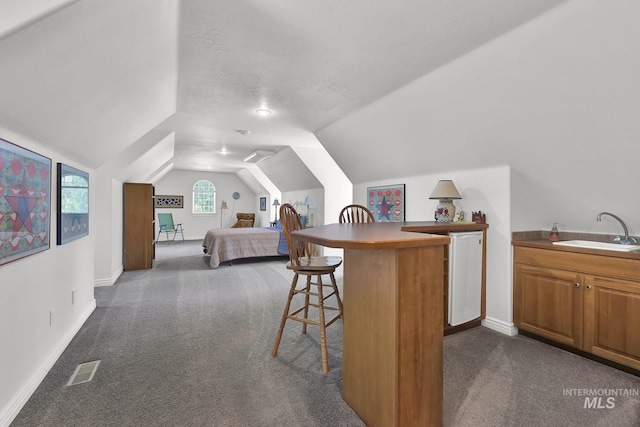 bedroom with dark carpet, a sink, baseboards, and lofted ceiling